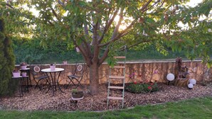 A garden patio with a tree, a stone wall, and outdoor furniture. - Beautiful spacious apartment (Gaukönigshofen)
