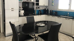 A modern kitchen with white cabinets, a black countertop, and a dining table with chairs. - In Casteljaloux at the door of the Landes pretty villa of 190m² - French property (Casteljaloux)