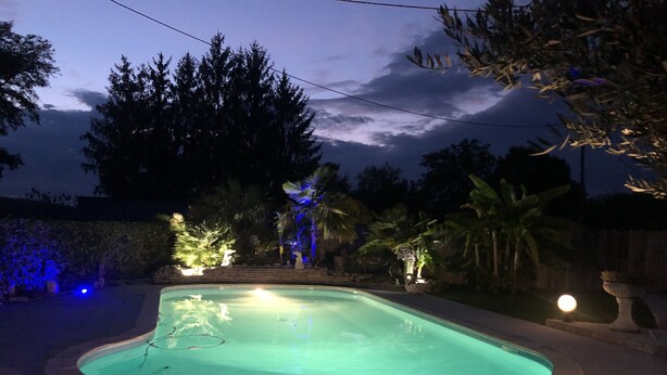 A swimming pool with a curved edge, surrounded by a stone deck. - In Casteljaloux at the door of the Landes pretty villa of 190m² - French property (Casteljaloux)