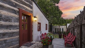 A rustic wooden building with a red door and a white exterior. There are potted plants and red chairs outside. - Authentic 1770's Home/PERFECT LOCATION/Steps to Marktplatz/Main! Hummingbird (Fredericksburg)
