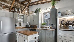 A kitchen with white cabinetry, a wooden island, and a coffee-themed sign. - Authentic 1770's Home/PERFECT LOCATION/Steps to Marktplatz/Main! Hummingbird (Fredericksburg)