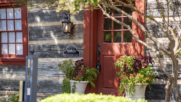 A wooden cabin with a red door, a welcome sign, and potted plants. - Authentic 1770's Home/PERFECT LOCATION/Steps to Marktplatz/Main! Hummingbird (Fredericksburg)