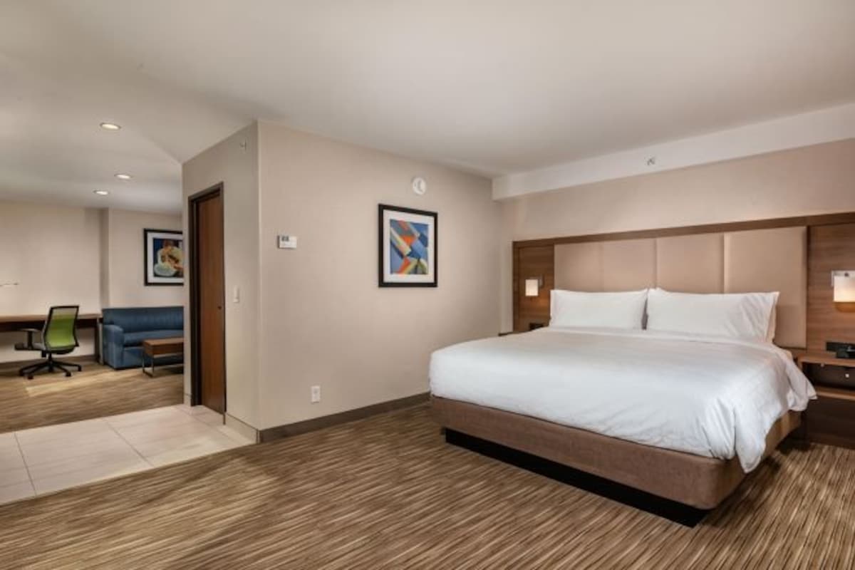 Une chambre d’hôtel avec un grand lit, un bureau, une chaise et un canapé.