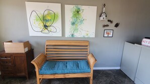 A room with a wooden bench, a cabinet, and artwork on the wall. - Town & Country Motel (Fort Stockton)