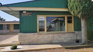 A building with a green exterior, a stone base, and a 'VACANCY' sign in the window. - Town & Country Motel (Fort Stockton)