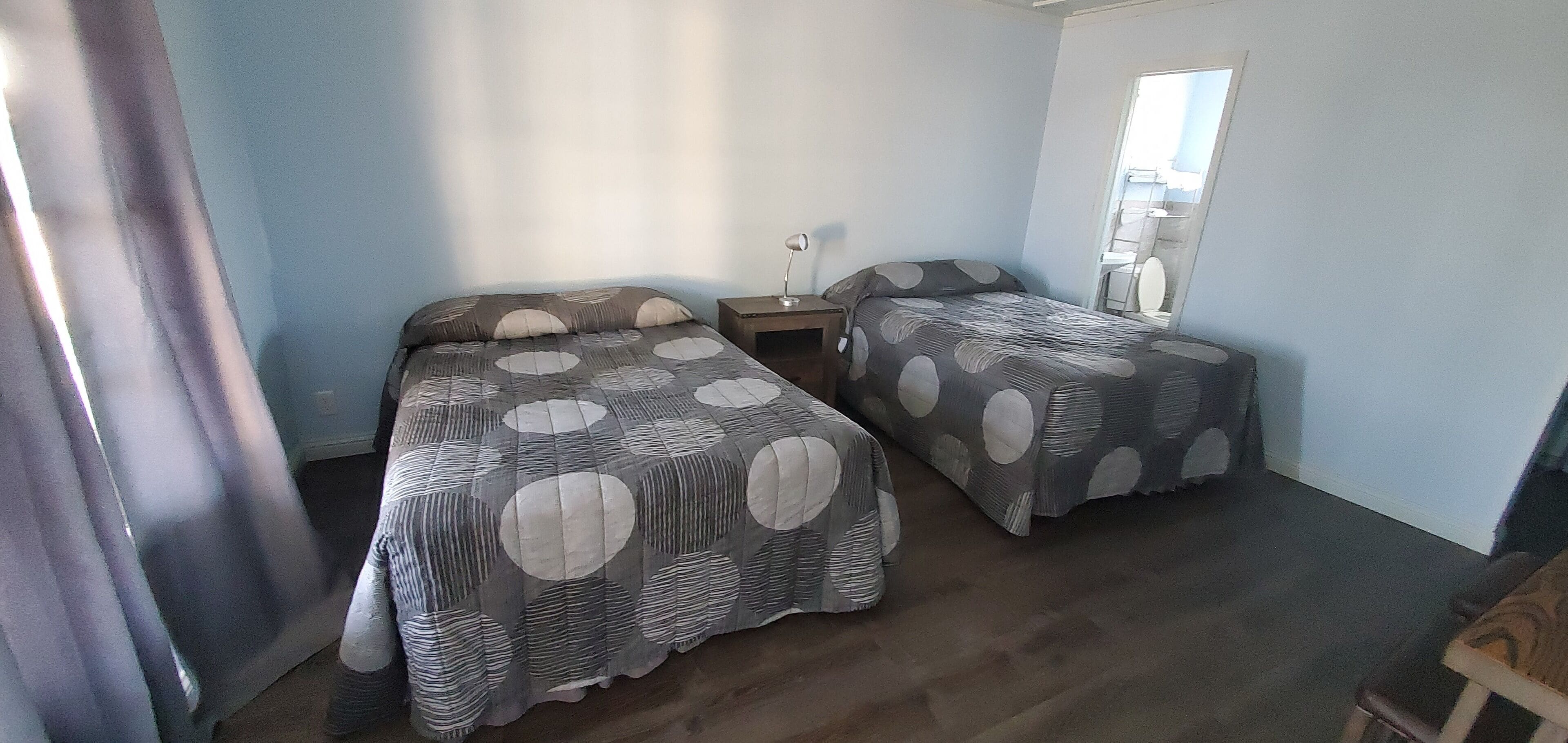 A bedroom with two beds, a nightstand, and a mirror.
