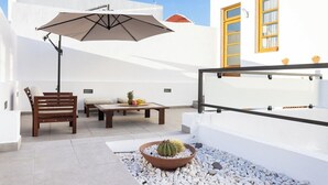Un patio con una panca di legno, un tavolo con frutta e un cactus in vaso.