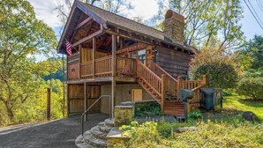 Een rustieke houten chalet met een veranda en een trap naar de ingang.