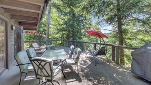 An outdoor deck with a table and chairs, a red umbrella, and a grill. - Peace on the Lake...close to Downtown Charlevoix (Charlevoix)