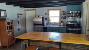 A kitchen with a wooden table, a refrigerator, a stove, and teal cabinets.