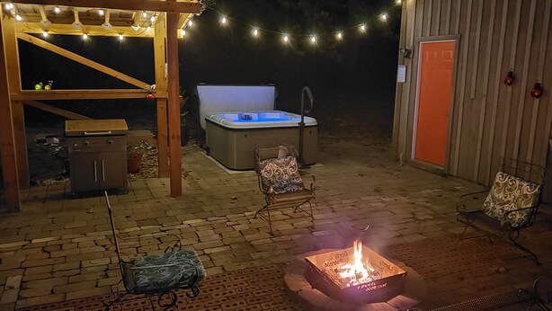 An outdoor patio with a hot tub, fire pit, and outdoor seating.