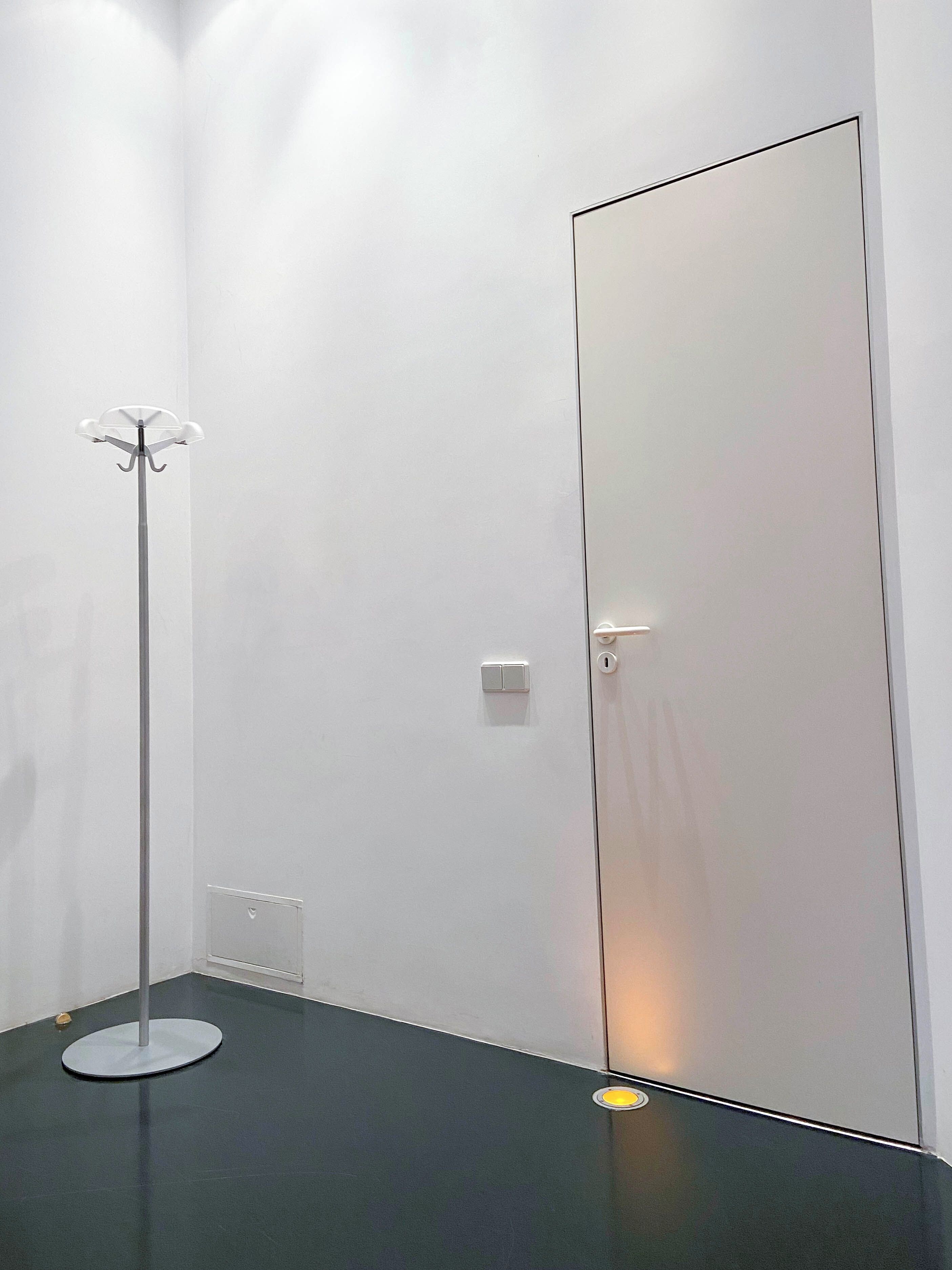A minimalist room with a floor lamp, a door, and a light switch.