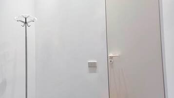 A minimalist room with a floor lamp, a door, and a light switch.