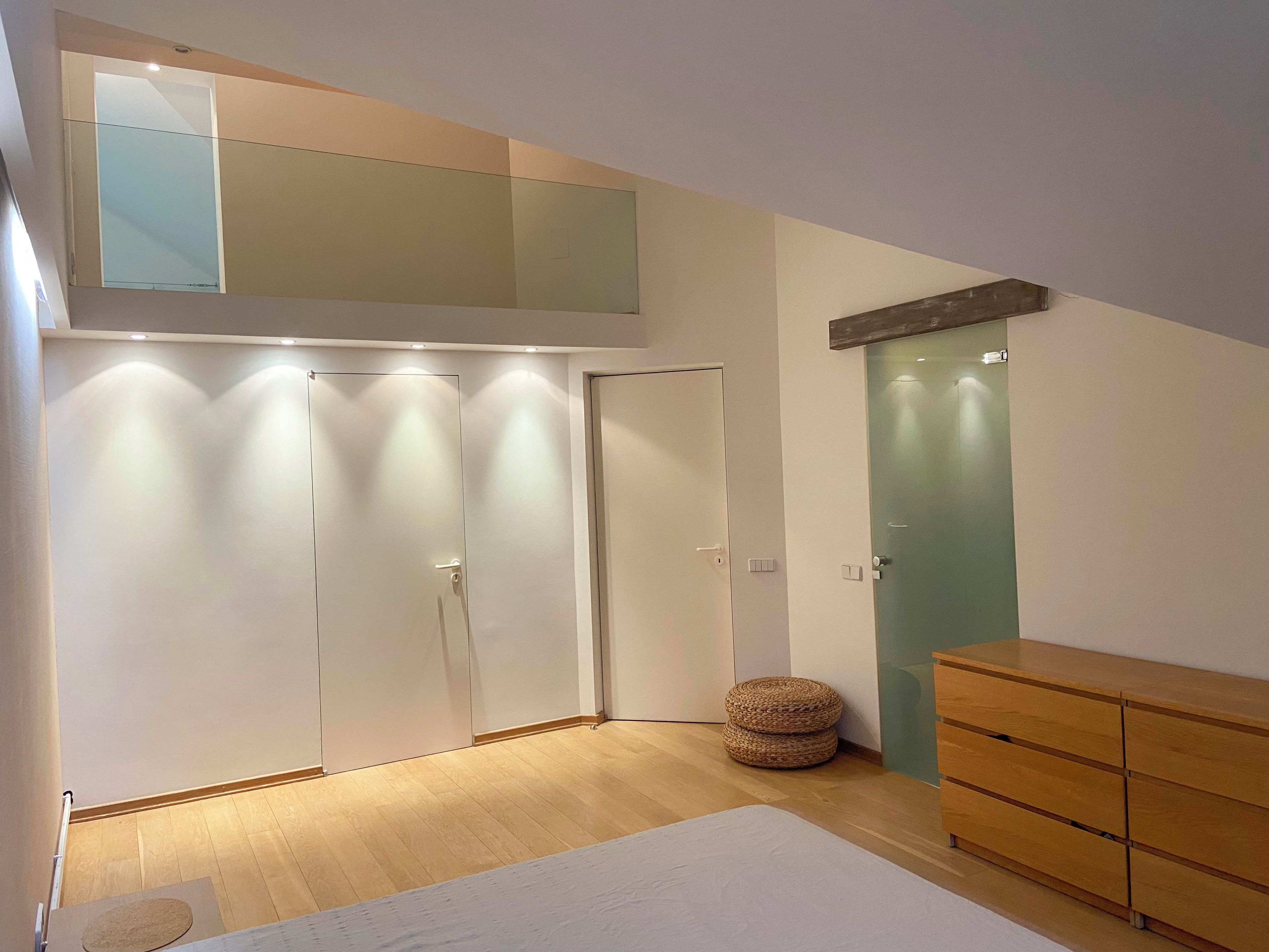 A room with a bed, a wardrobe, a green door, and a wooden dresser.