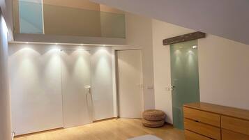 A room with a bed, a wardrobe, a green door, and a wooden dresser.
