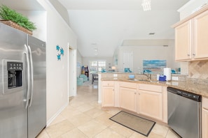 Uma cozinha moderna com eletrodomésticos de aço inoxidável, bancadas de granito e armários de madeira clara.