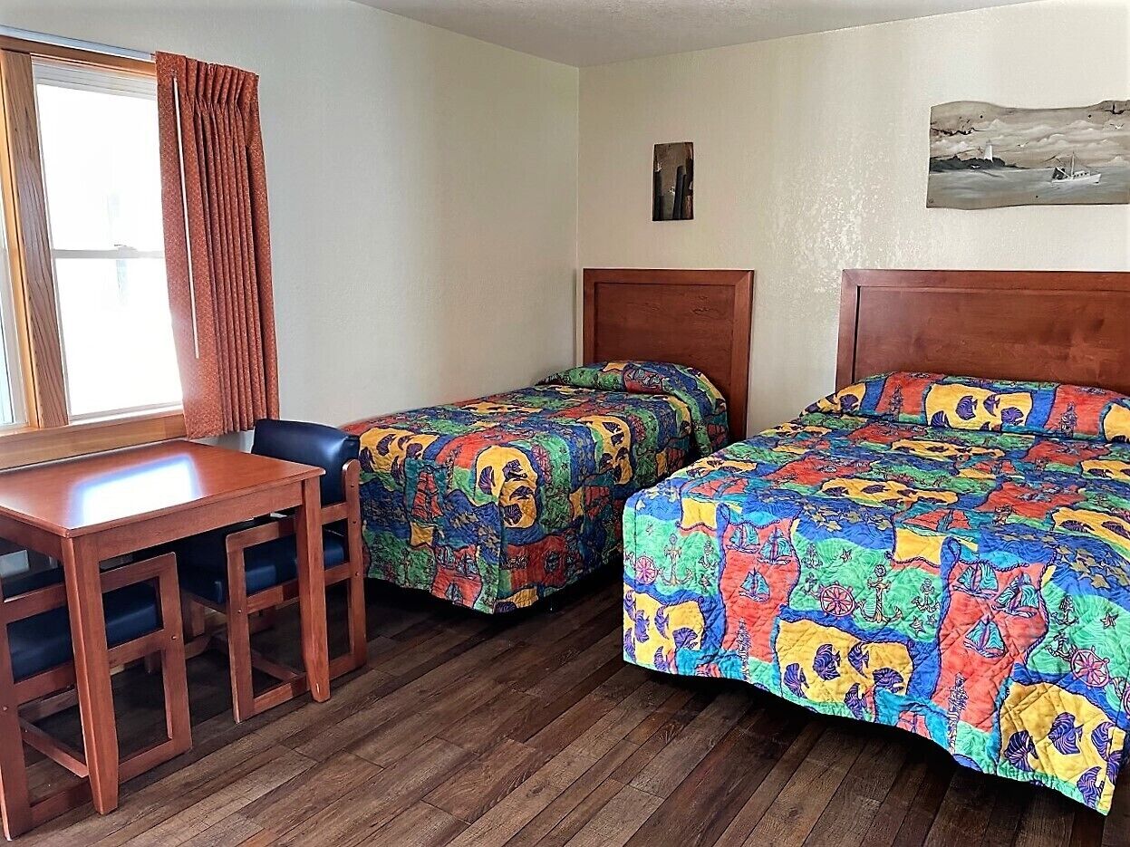 Une chambre avec deux lits, un bureau en bois et des chaises.
