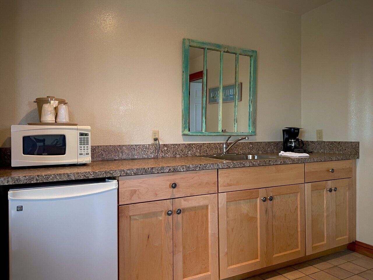 A kitchen with wooden cabinets, a microwave, a refrigerator, a sink, and a coffee maker.
