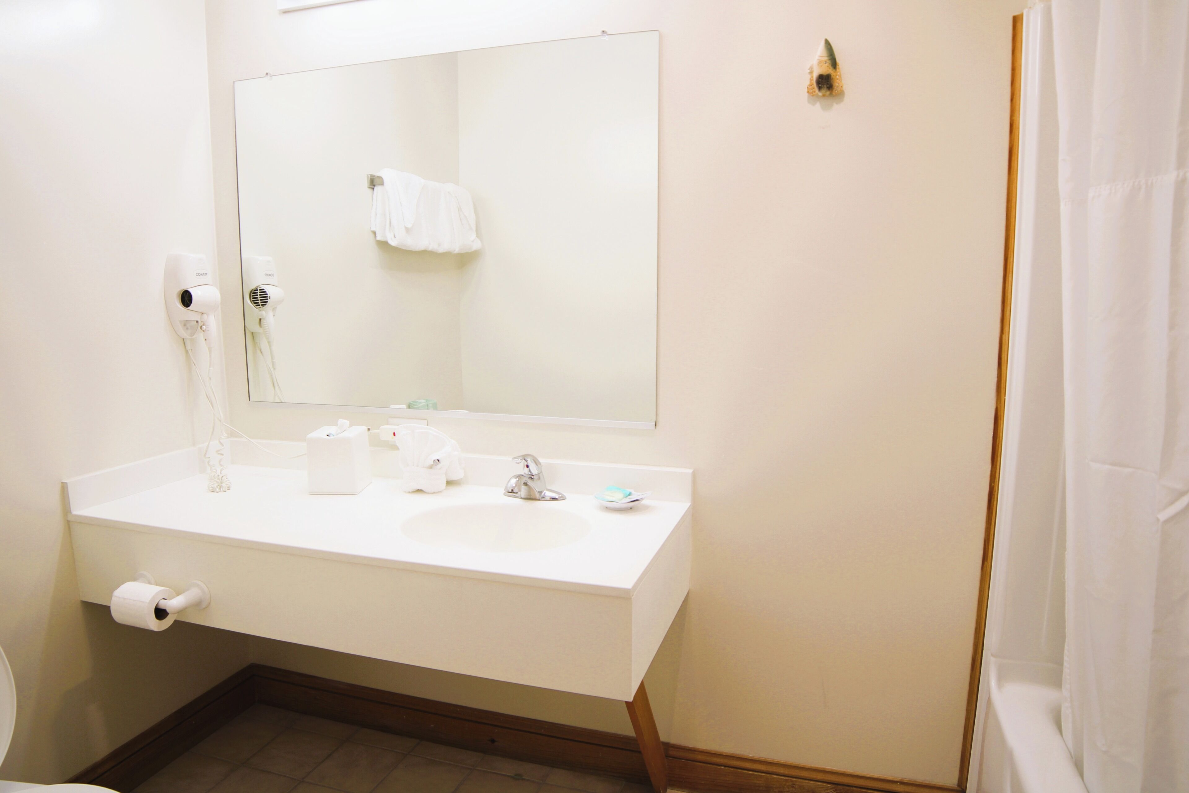 A bathroom with a white sink, a mirror, a towel hanging on the wall, and a toilet.