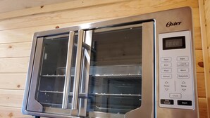 Un horno microondas Oster de acero inoxidable con pantalla digital, horno integrado y puerta de cristal.