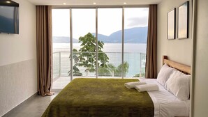 Une chambre d’hôtel avec un grand lit, une vue sur la mer et un balcon.