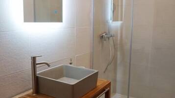 Une salle de bain avec une douche à parois de verre, un meuble-lavabo en bois et un miroir au-dessus du meuble-lavabo.