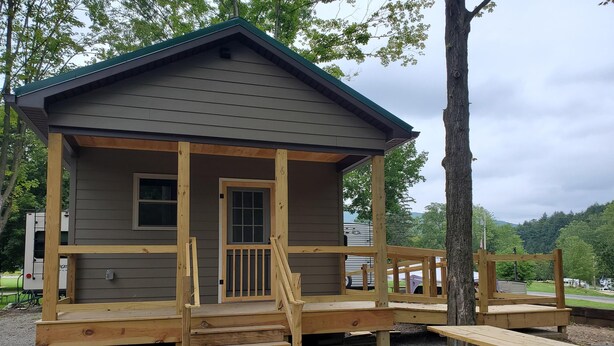 A wooden cabin with a porch, a door, and a window.