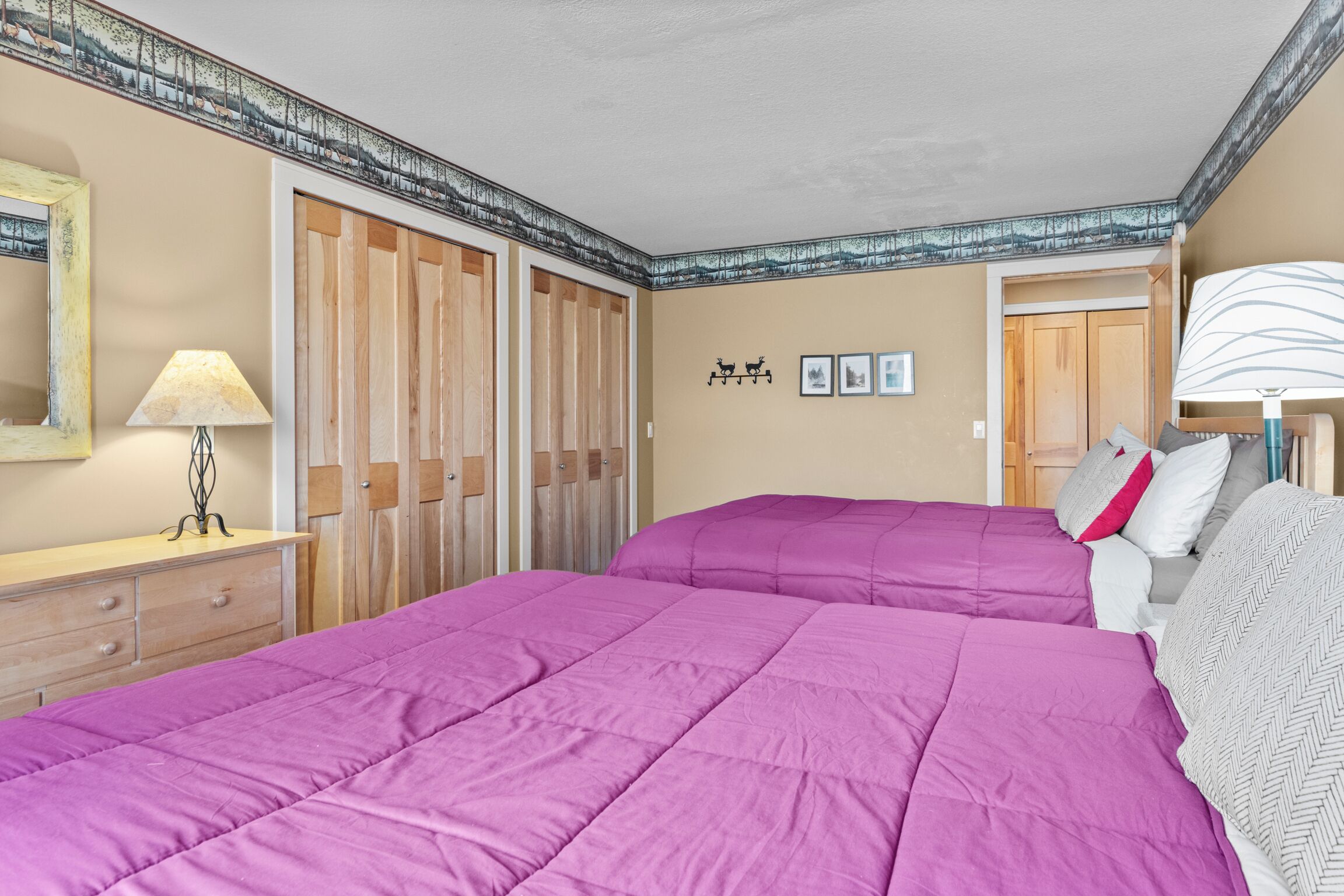 Un dormitorio con una cama grande, un armario de madera, un espejo y una pared con cuadros enmarcados.