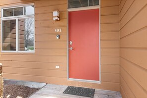 A house with a red door, a number 403, and a window with a view of trees.