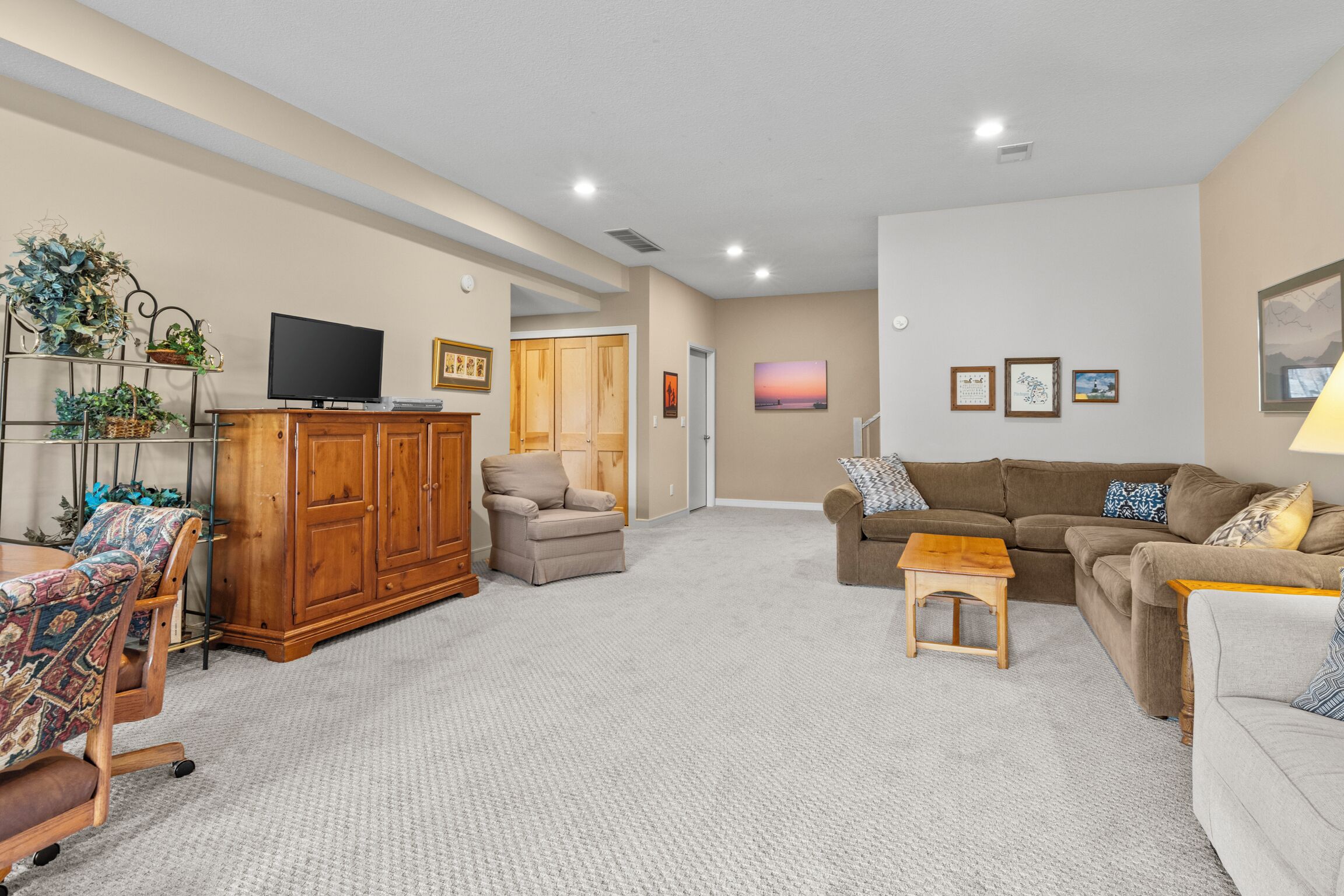 A living room with a TV, sofa, armchair, and a small table.
