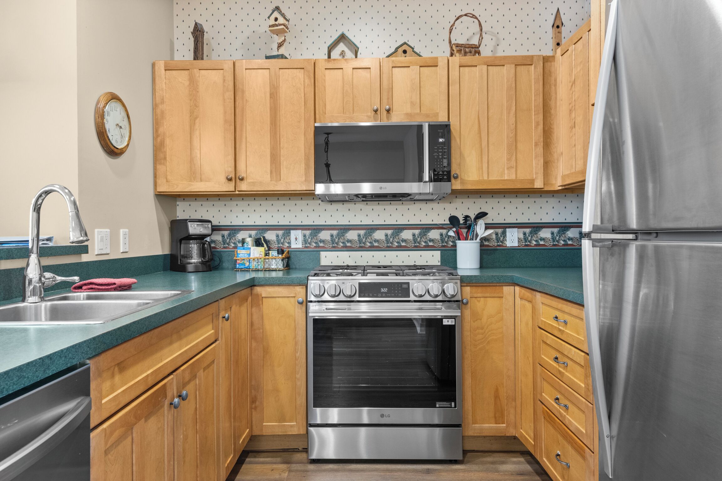 A kitchen with wooden cabinets, a stainless steel microwave, an oven, and a refrigerator.