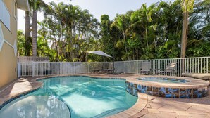 A swimming pool with a tiled edge, surrounded by a fence and palm trees. - Paradise in Naples (Naples)