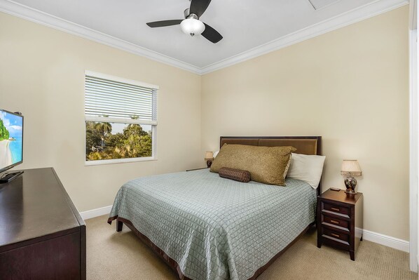 A bedroom with a bed, a nightstand, a lamp, a TV, and a window with blinds. - Paradise in Naples (Naples)
