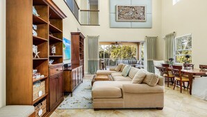 A spacious living area with a beige sectional sofa, wooden shelving, and a dining table with chairs. - Paradise in Naples (Naples)