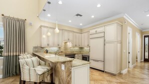 A kitchen with a central island, bar stools, and pendant lighting. - Paradise in Naples (Naples)