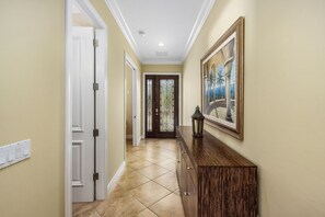 Stylish hallway with a dresser, painting, and lantern, leading to a door with a glass panel.