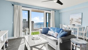 A modern living room with a balcony, white furniture, and a view of the ocean. - SMOOTH SAILING-BEAUTIFULLY DECORATED, GULF VIEWS (Panama City Beach)