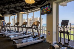 Une salle de sport équipée de tapis de course, d’un appareil elliptique et d’un écran de télévision.