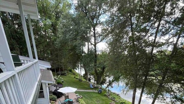 Un jardin avec une terrasse, un petit étang et une pelouse.