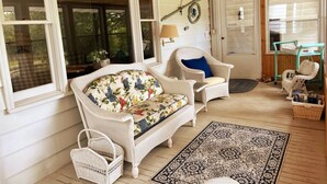 Une véranda accueillante, avec des meubles en osier, un tapis à motifs et un panier en osier.