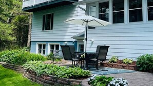 Une maison à deux étages avec un balcon, une terrasse dotée de mobilier d’extérieur et un jardin.