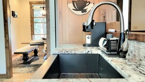 Una cocina moderna con encimera de granito, pileta de acero inoxidable y protector de pared de madera.