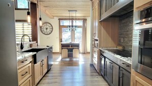 Una cocina moderna con armarios de madera, una isla central y vistas al exterior a través de amplios ventanales.