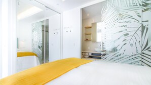 Une chambre d’hôtel moderne équipée d’un lit, d’une douche et d’une salle de bain avec un lavabo et un miroir.