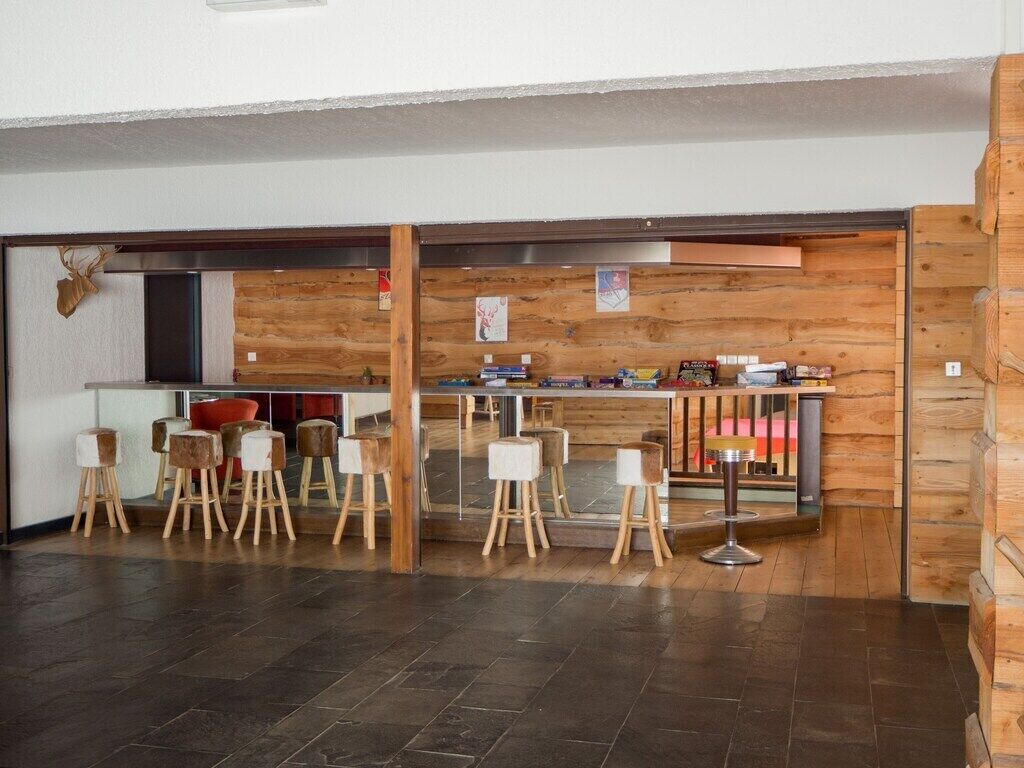 Un interior moderno con una zona de bar, paredes de madera y varios taburetes.