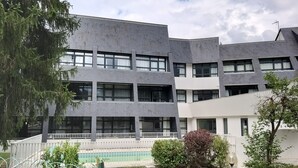 Un edifici de diverses plantes amb un disseny arquitectònic modern, amb teulada plana i grans finestres.