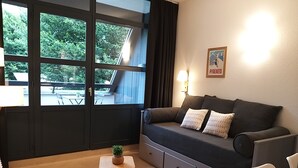 Un saló modern amb un sofà, dues taules laterals, una planta petita i un pòster a la paret.