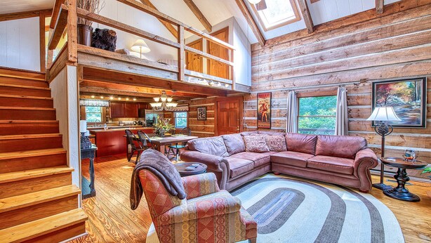 Un interior espacioso de cabaña de madera con una amplia sala de estar, un comedor y una cocina.