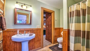 A bathroom with a wooden vanity, a sink, a mirror, and a shower curtain.
