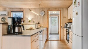 Una cocina moderna con paneles de madera, una cafetera, un hervidor y un refrigerador.